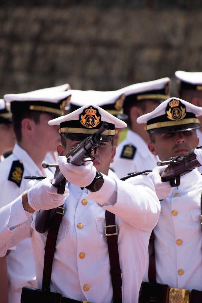 Navy officers in uniform perform a ceremonial drill with rifles, showcasing discipline and precision.