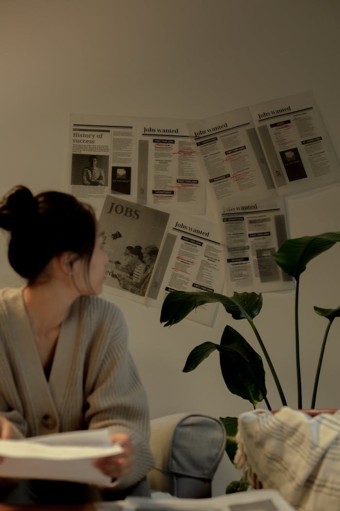 services-02 A woman in a cozy setting reviews job listings on a wall, exuding a thoughtful mood.